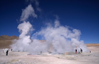 BOLIVIA, Potosi, Sol de la Manana, Tourists amongst steam rising from geothermal geysers.