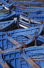 MOROCCO, Essaouira, Prows of blue and green fishing boats moored closely together.