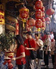 THAILAND, Bangkok, China Town, Wat Traimit.  People offering prayers and incense at temple