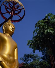 THAILAND, Bangkok, Sathorn District, Charoen Krung.  Golden Buddha statue in temple grounds.