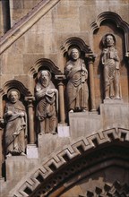 HUNGARY, Budapest, Benedictine Abbey of Jak. Detail of carved religious figures over stone archway.
