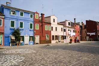ITALY, Veneto, Venice, Colourful houses in a square on Burano. One of the few inhabited islands in