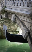 ITALY, Veneto, Venice, The Ferro at the bow of a gondola passing under a footbridge over a canal