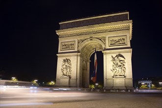 FRANCE, Ile de France, Paris, Streaked lights of traffic passing the Arc de Triomphe illuminated at
