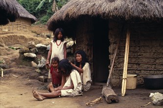 COLOMBIA, Sierra Nevada de Santa Marta, Kogi-Wiwa family outside mud-wattle/grass thatched home in