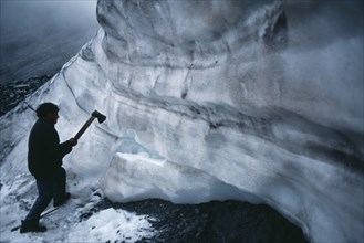 BOLIVIA, La Paz, La Rinconada, Ice hunter using axe to cut blocks of ice near La Cumbre.