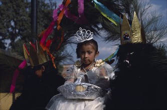 MEXICO, Tlaxcala, Little girl dressed in white flanked by two masked attendants in costume on float
