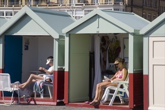 ENGLAND, East Sussex, Brighton, People relaxing their beach huts at the seafront on Hove lawns.
