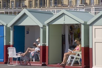 ENGLAND, East Sussex, Brighton, People relaxing their beach huts at the seafront on Hove lawns.