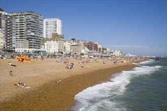 ENGLAND, East Sussex, Brighton, The beach with seafront apartment building behind.