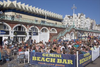 ENGLAND, East Sussex, Brighton, People sat outside the Beach Bar on the seafront.