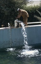 QATAR, Agriculture, Man letting water into irrigation pool on a farm