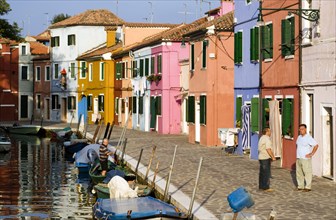 ITALY, Veneto, Venice, Colourful houses beside a canal on the lagoon island of Burano with people