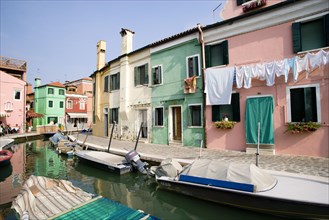 ITALY, Veneto, Venice, Colourful houses beside a canal on the lagoon island of Burano with boats