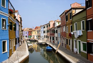 ITALY, Veneto, Venice, Colourful houses beside a canal on the lagoon island of Burano with tourists
