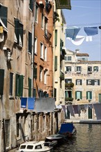 ITALY, Veneto, Venice, Washing hanging from lines above a canal from buildings in the Ghetto. The