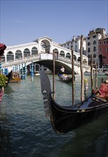 ITALY, Veneto, Venice, A gondola moored at the edge of the Grand Canal with another carrying