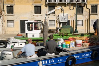 ITALY, Veneto, Venice, Painters and decorators wait to moor their boat on the Grand Canal whilst a