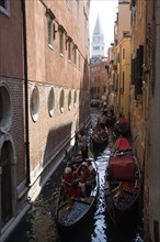 ITALY, Veneto, Venice, Gondoliers carry sightseeing tourists in gondolas along the norrow Rio di