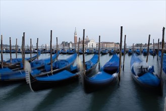 ITALY, Veneto, Venice, Gondolas moored at dusk in the Molo San Marco basin with Palladio's church
