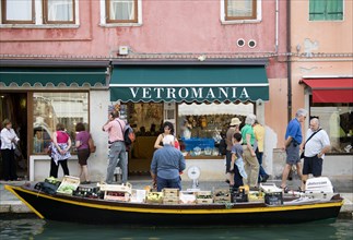 ITALY, Veneto, Venice, A fruit and vegetable vendor with his boat moored alongside the Fondamenta