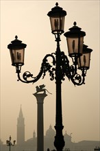 ITALY, Veneto, Venice, An ornate lamp post and the Column of Saint Mark in the Piazzetta with