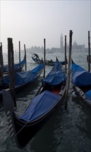 ITALY, Veneto, Venice, A gondolier works his gondola past others moored at the Molo San Marco with