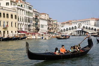 ITALY, Veneto, Venice, Sightseeing tourists in a Gondola on the Grand Canal with the Rialto Bridge