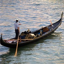 ITALY, Veneto, Venice, A gondolier with sightseeing tourists in his gondola on the Grand Canal