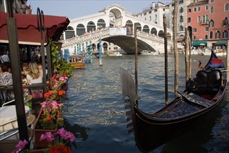 ITALY, Veneto, Venice, A gondola moored beside a restaurant on the Grand Canal with tourists dining