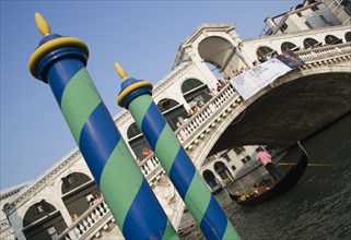 ITALY, Veneto, Venice, Colourful posts for mooring boats in front of gondolas carrying sightseers