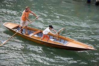 ITALY, Veneto, Venice, Man and young boy rowing a traditional boat in the gondola manner along the