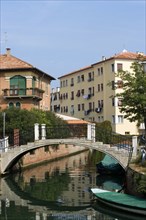 ITALY, Veneto, Venice, Housing beside a bridge crossing a canal with moored boats on the Lido