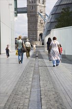 ENGLAND, London, People walking passed man made stream toward GLA town hall and Tower Bridge.