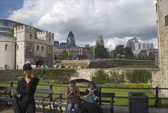 ENGLAND, London, Tourists using their mobile phone outside the Tower of London with the Gherkin