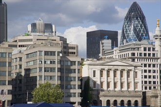 ENGLAND, London, "The Gherkin Swiss Re building seen, through tightly huddled buildings in the