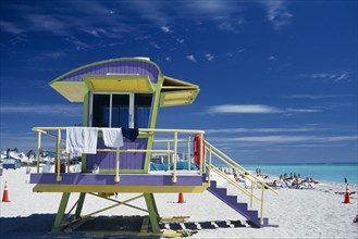 USA, Florida, Miami, South Beach. Colourful Lifeguard Station on sandy beach with sunbathers near
