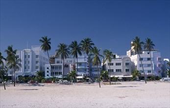 USA, Florida, Miami , South Beach. View across sandy beach with palm trees towards Ocean Drive Art