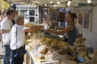 ENGLAND, West Sussex, Shoreham-by-Sea, French Market. Selection of breads on stall with customers