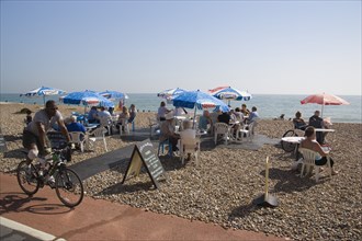ENGLAND, West Sussex, Worthing, Beach front Cafe with people sitting at tables under parasols on