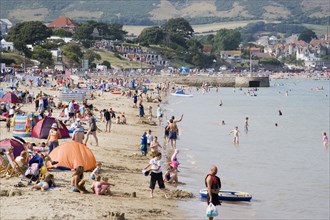 ENGLAND, Dorset, Swanage Bay, View along the shoreline of sandy beach with sunbathers on the sand