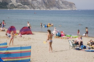 ENGLAND, Dorset, Swanage Bay, Sandy beach with girls playing Bat and Ball amongst sunbathers on