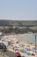 ENGLAND, Dorset, Swanage Bay, Elevated view over busy colourful sandy beach with sunbathers on the