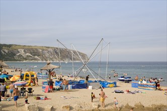 ENGLAND, Dorset, Swanage Bay, Busy colourful sandy beach scattered with inflatables and windbreaks