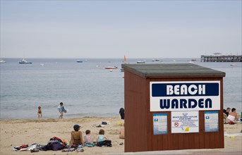 ENGLAND, Dorset, Swanage Bay, Beach Warden hut on sandy beach with sunbathers on the sand