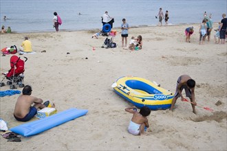ENGLAND, Dorset, Swanage Bay, Sunbathers and children playing on sandy beach near inflatables and a