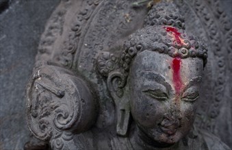 NEPAL, Kathmandu, Detail of Buddha statue anointed with pink powder.
