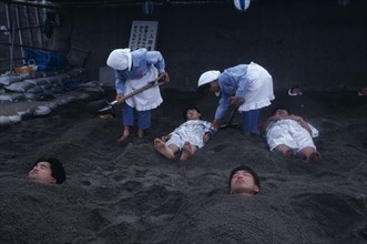 JAPAN, Kyushu, Ibusuki, Sunabulo. Hot Sand Bath with people being covered in sand by two women