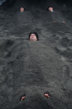 JAPAN, Kyushu, Ibusuki, Sunabulo. Hot Sand Bath with men submerged in sand with only heads and feet