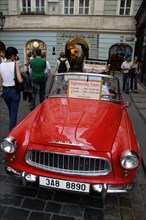 CZECH REPUBLIC, Bohemia, Prague, "Tourists walking past a red Skoda, parked in the street, used for